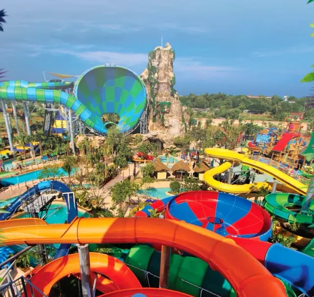 Colorful water slides winding around an artificial rock and pools below