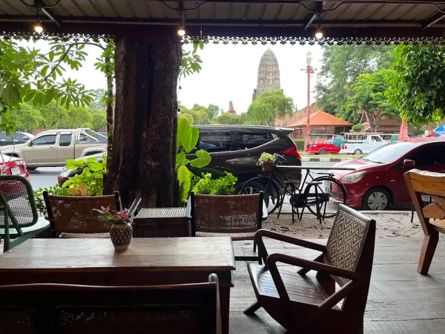 A view from covered wooden tables toward a brick temple spire across the road