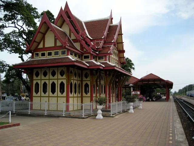 A red and white royal style wooden railway pavilion beside a platform and track