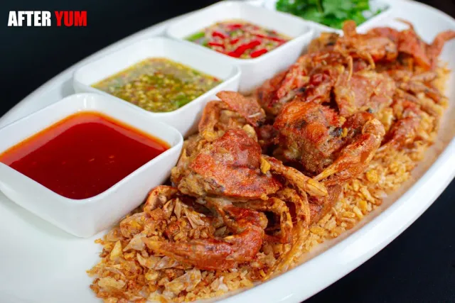 A platter with fried crabs over fried rice and four small bowls of sauces