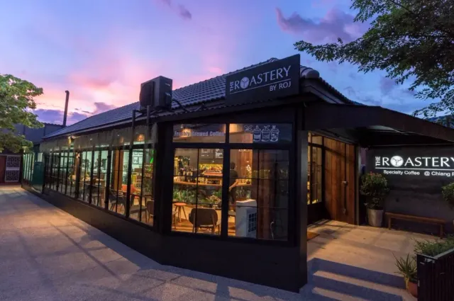 A black building with lit glass walls at dusk, a purple sky above it