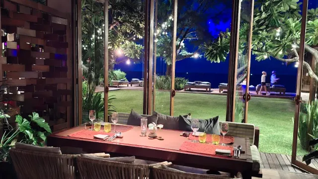 A table set in the evening facing a lit lawn and a blue sea line on the horizon