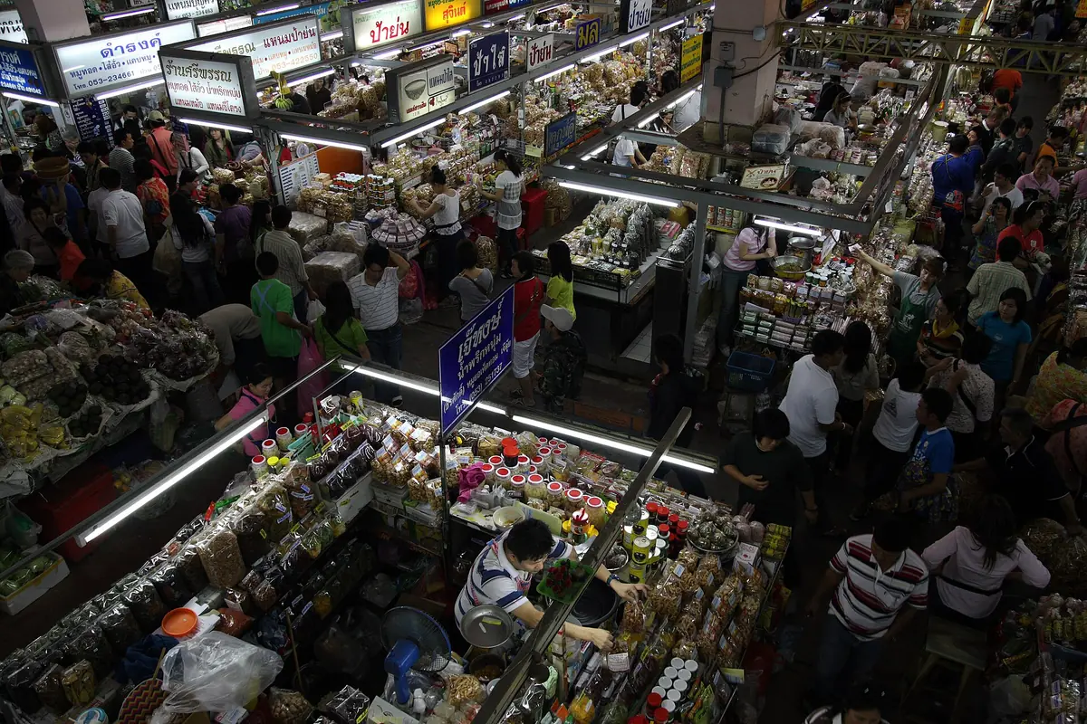An overhead view of a packed market hall with dry goods stalls and shoppers in the aisles