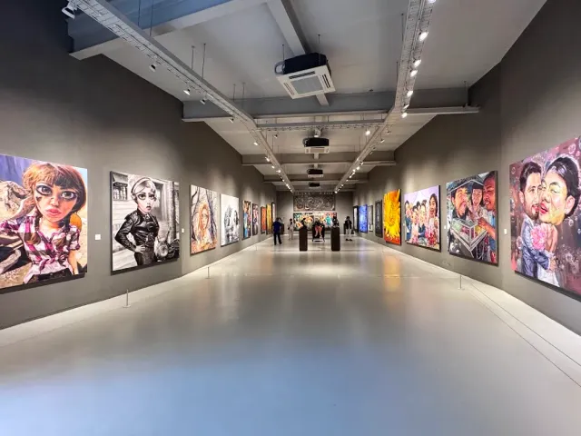 A long gallery hall with large portrait paintings hanging on both sides of the aisle