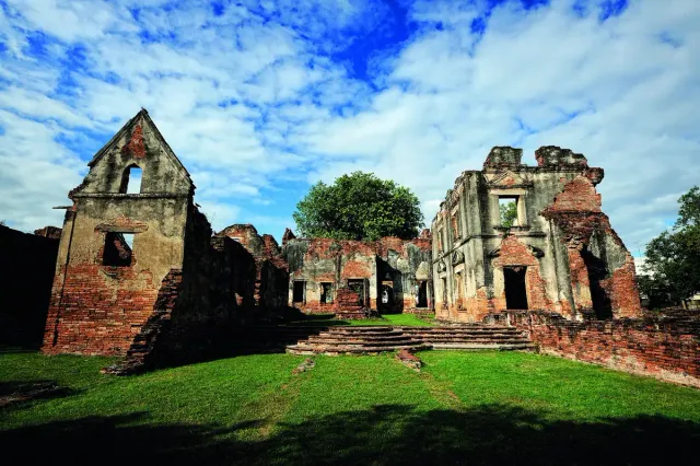 The brick remains of a building with tall arched windows on a green lawn