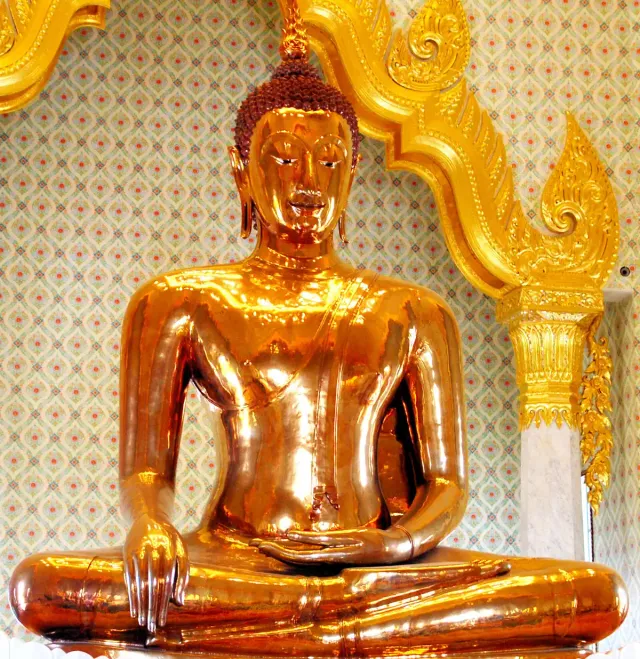A seated Buddha figure in polished gold inside a temple hall