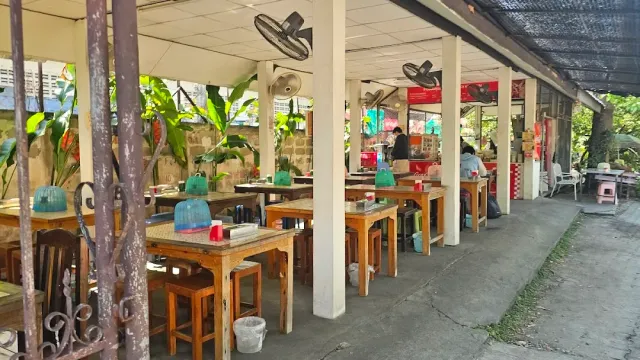 An open seating area with wooden tables, stools and wall fans above
