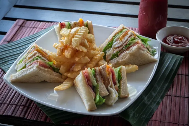 Triangular club sandwiches with crinkle-cut fries on a white plate