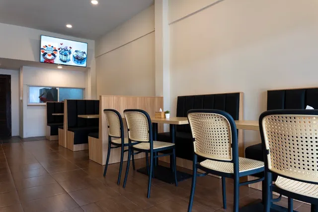 A clean seating area with wicker chairs, black booths and a screen on the wall
