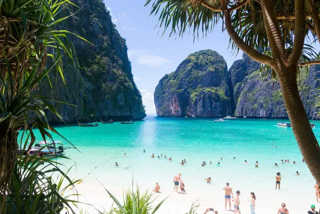 A white sand bay in turquoise water enclosed by tall forested limestone cliffs