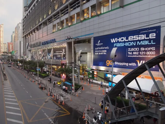 A shopping centre building with large fashion signage and a busy pavement in front