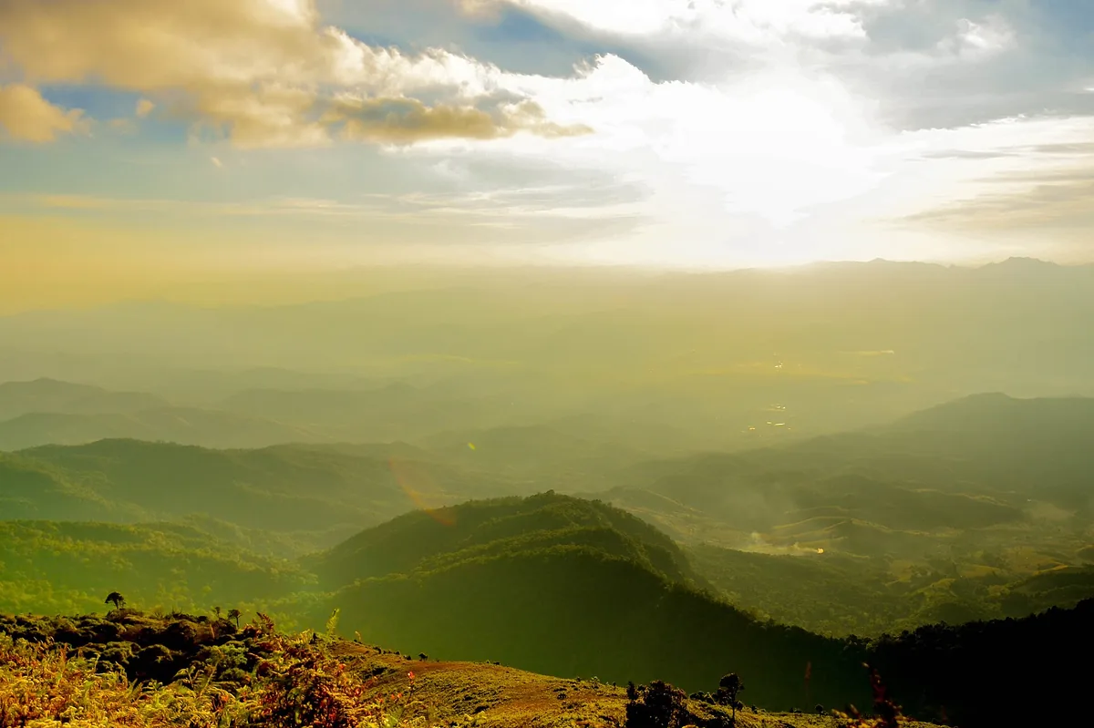 Layered green mountain ridges in soft mist and backlight