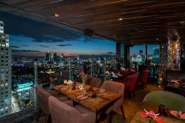 Set tables beside a high window, with a view of the city skyline at dusk