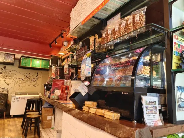 A counter with a pastry case, hanging snack bags and a red ceiling