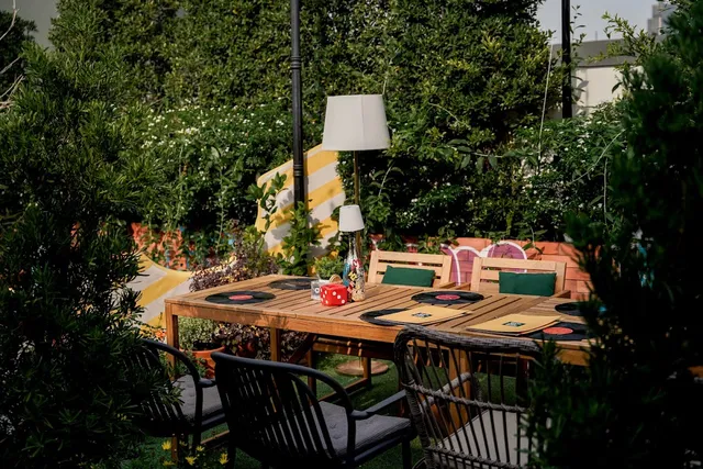 A wooden table set with vinyl records as placemats, inside a green rooftop garden