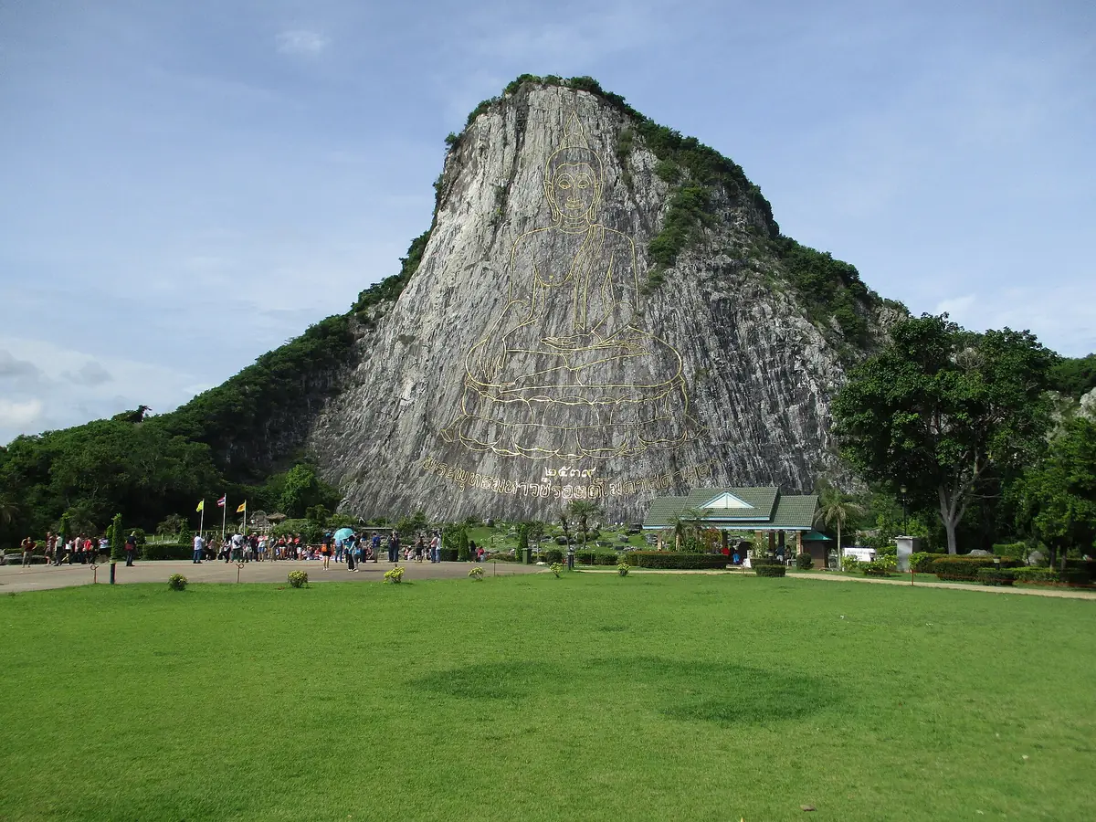 The Buddha figure carved into the Khao Chi Chan cliff above a broad lawn