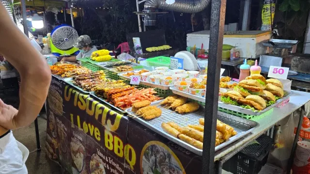 A grill stall in the evening, skewers, fried chicken and sandwiches arranged on the counter