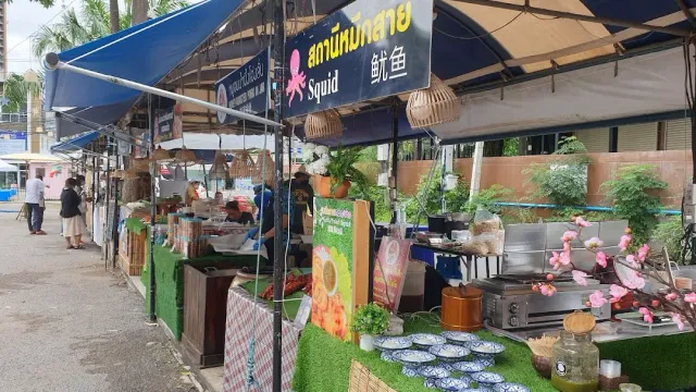 A row of stalls with blue awnings, potted plants and ceramic dishes on the counter