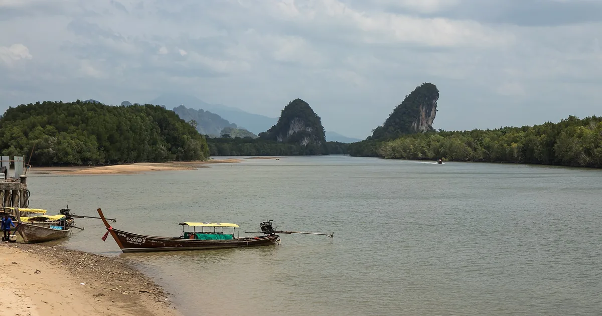 The two limestone peaks of Khao Khanab Nam above the river, longtail boats below