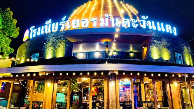 A domed building lit at night with a Thai neon sign and light strings
