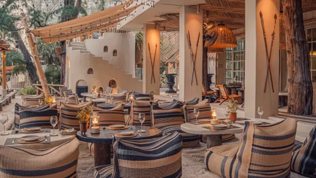 A beach lounge with striped poufs, low tables and candles, and oars on the columns