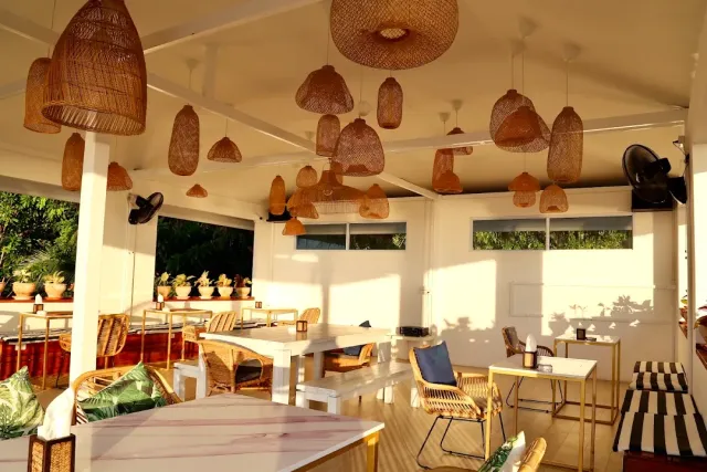 A white pavilion with dozens of rattan lamps hanging at different heights