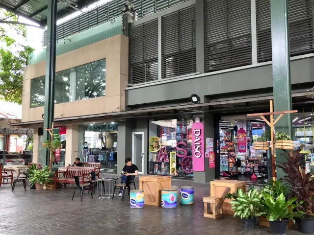 The facade of an open air shopping center, wooden tables and people sitting outside