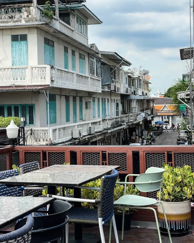 A rooftop terrace with tables and chairs, facing a row of old houses on the street