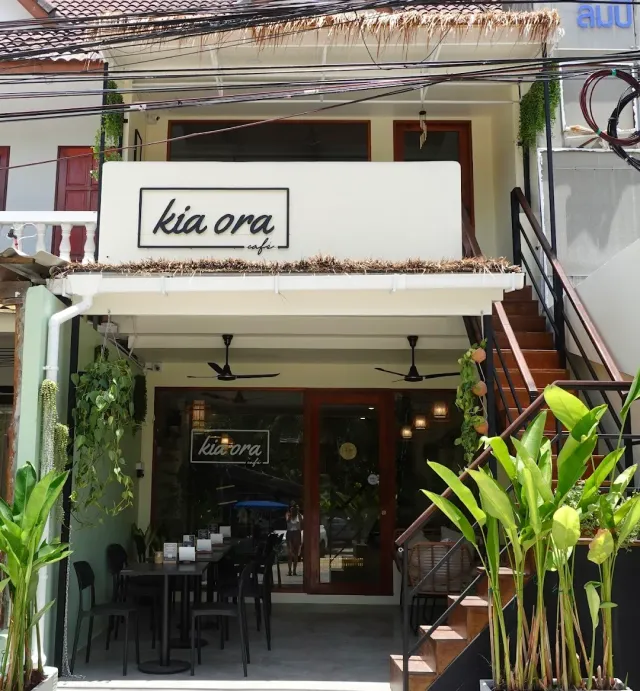 A white front of a two storey building with a framed sign and metal stairs to the side
