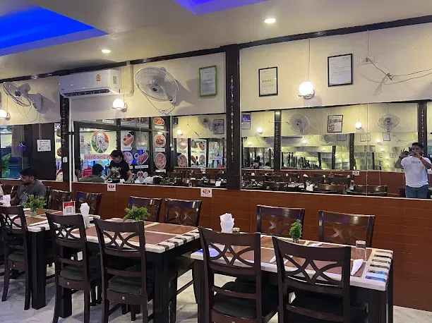 A hall with dark wooden tables, wall fans and framed certificates on the wall