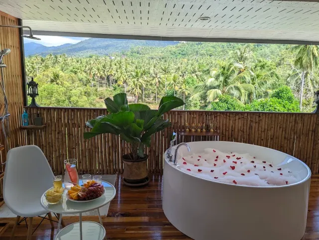 A round tub with foam and red petals, an open balcony facing a palm grove