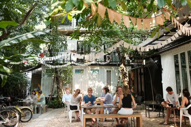 A garden courtyard with diners around tables, bunting strings and bicycles to the side