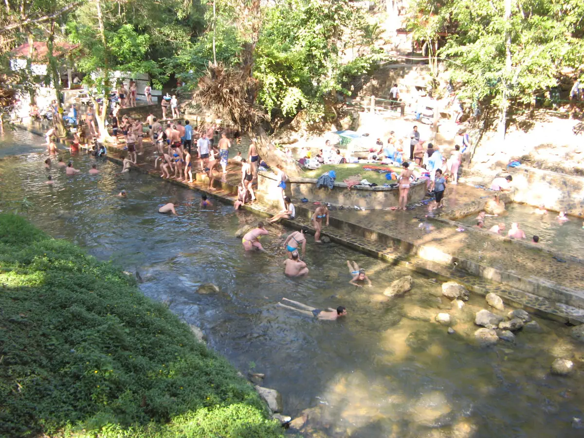 Natural pools on stone steps inside a forest with many bathers