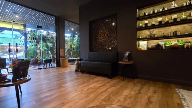 A lobby with a wooden floor, a black sofa, a carved panel and lit shelves