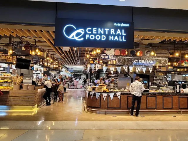 A food hall in a mall, lit delicatessen counters and a sign hanging above them