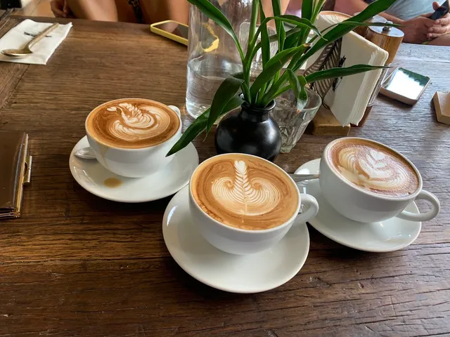 Three cups of coffee with latte art on a wooden table