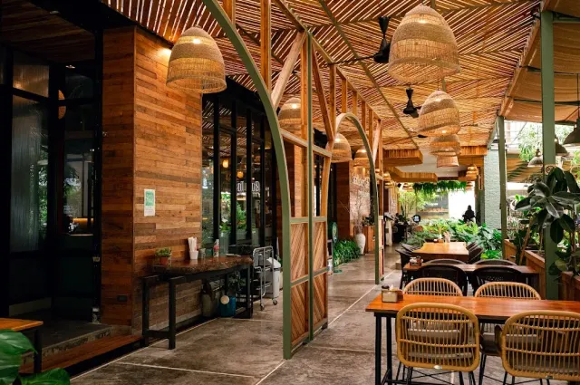 An open corridor with a bamboo ceiling, large rattan lamps and rattan chairs at wooden tables