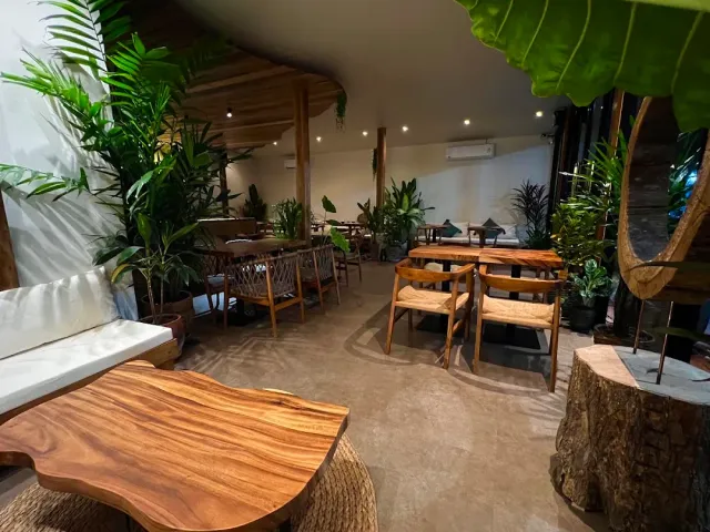 A space with dense greenery, live edge wooden tables and light chairs