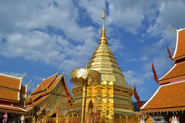 A gilded chedi rising above orange tile roofs and golden parasols