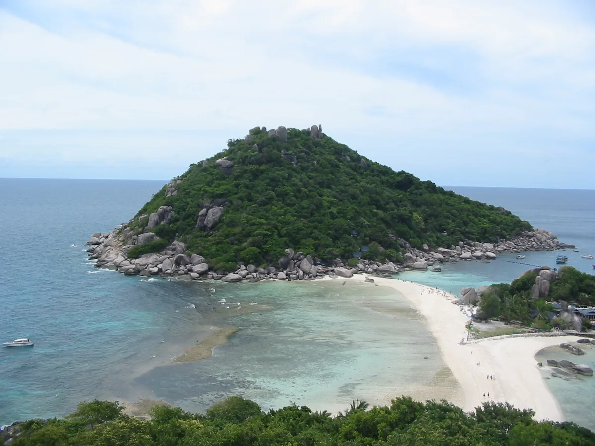 Summit view of a green island joined by a white sand strip between turquoise water