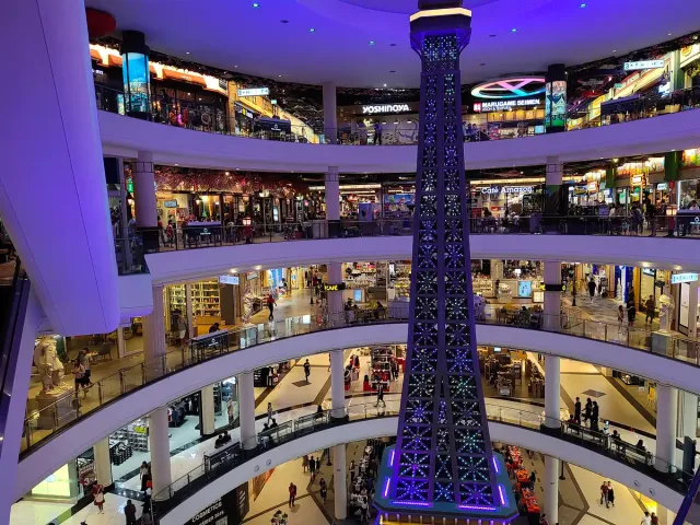 A multi level interior atrium lined with shops and lit in purple at its centre