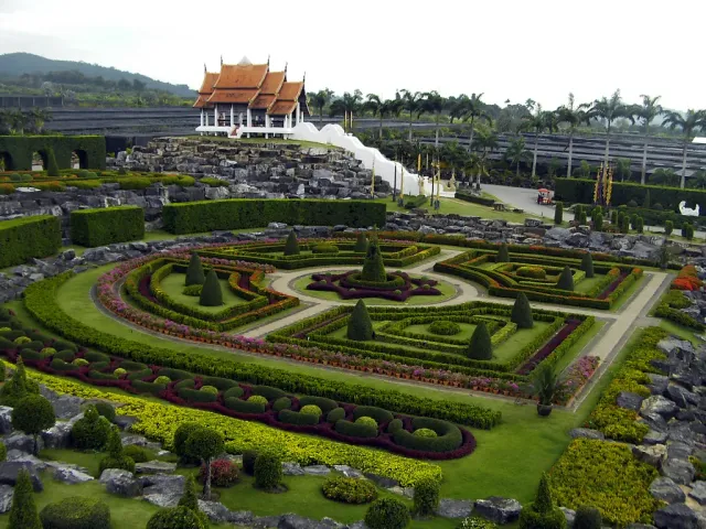A geometric ornamental garden with neat beds and clipped shrubs sloping towards a pavilion