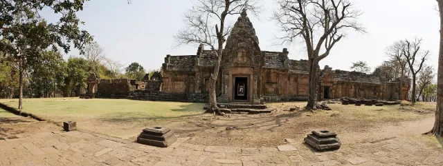 A carved sandstone sanctuary on a hill with steps and scattered stones around it