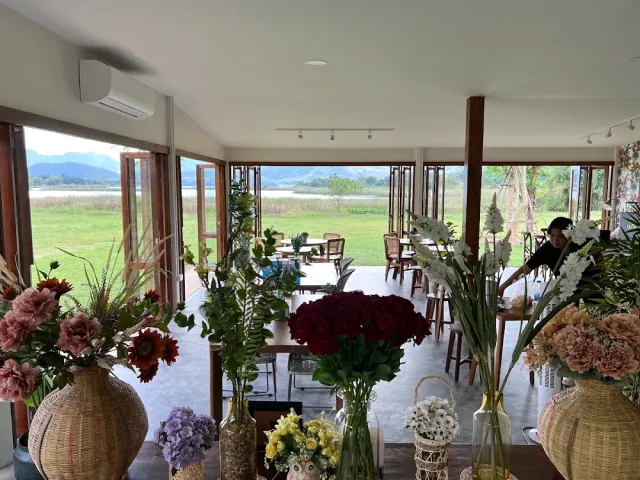 Flower vases in the foreground, open glass doors onto a green field and mountains