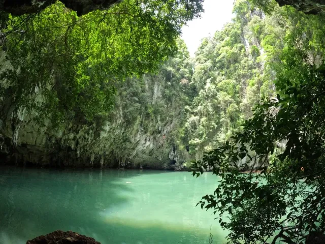 Emerald colored water between steep limestone cliffs covered in vegetation