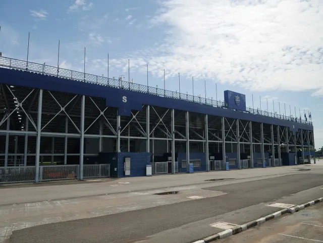 A blue football stadium stand with an exposed steel frame and an empty entrance apron
