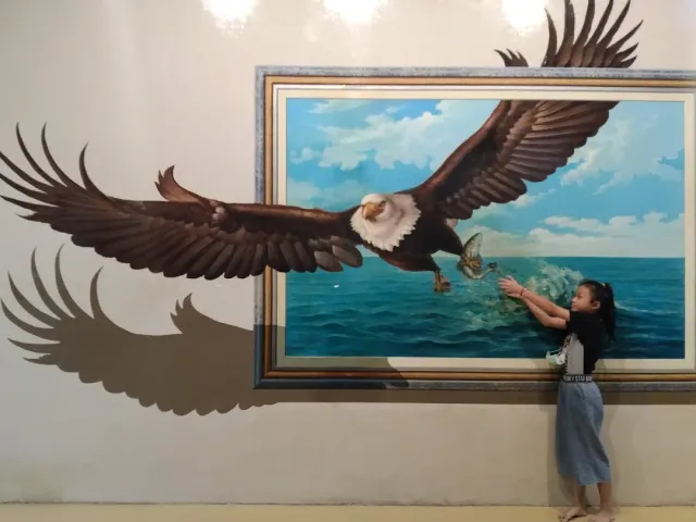 A girl reaching toward a painted eagle that seems to burst out of a frame on the wall