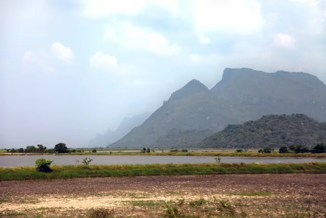 A jagged limestone ridge rising above green fields and a bright sky