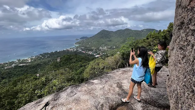 Hikers photograph the west coast and the green hills below from a granite rock