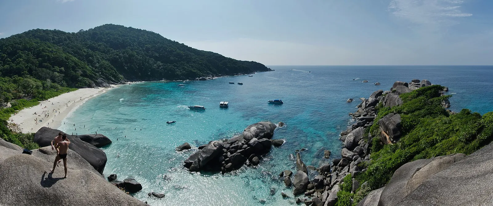 A white sand bay with granite boulders, turquoise water and dive boats at anchor in the Similan Islands, Thailand